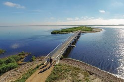 To cyklister på vej over en bro i solskinsvejr nær Søndervig